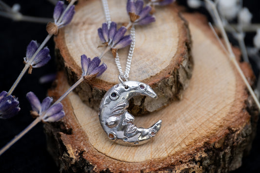 a silver crescent man in the moon pendant