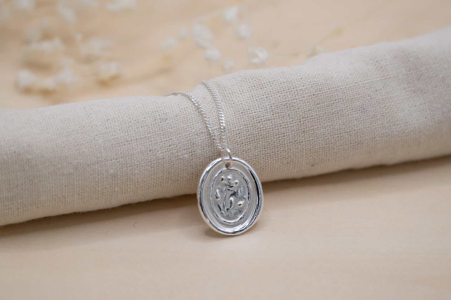 a floral wax seal necklace in silver