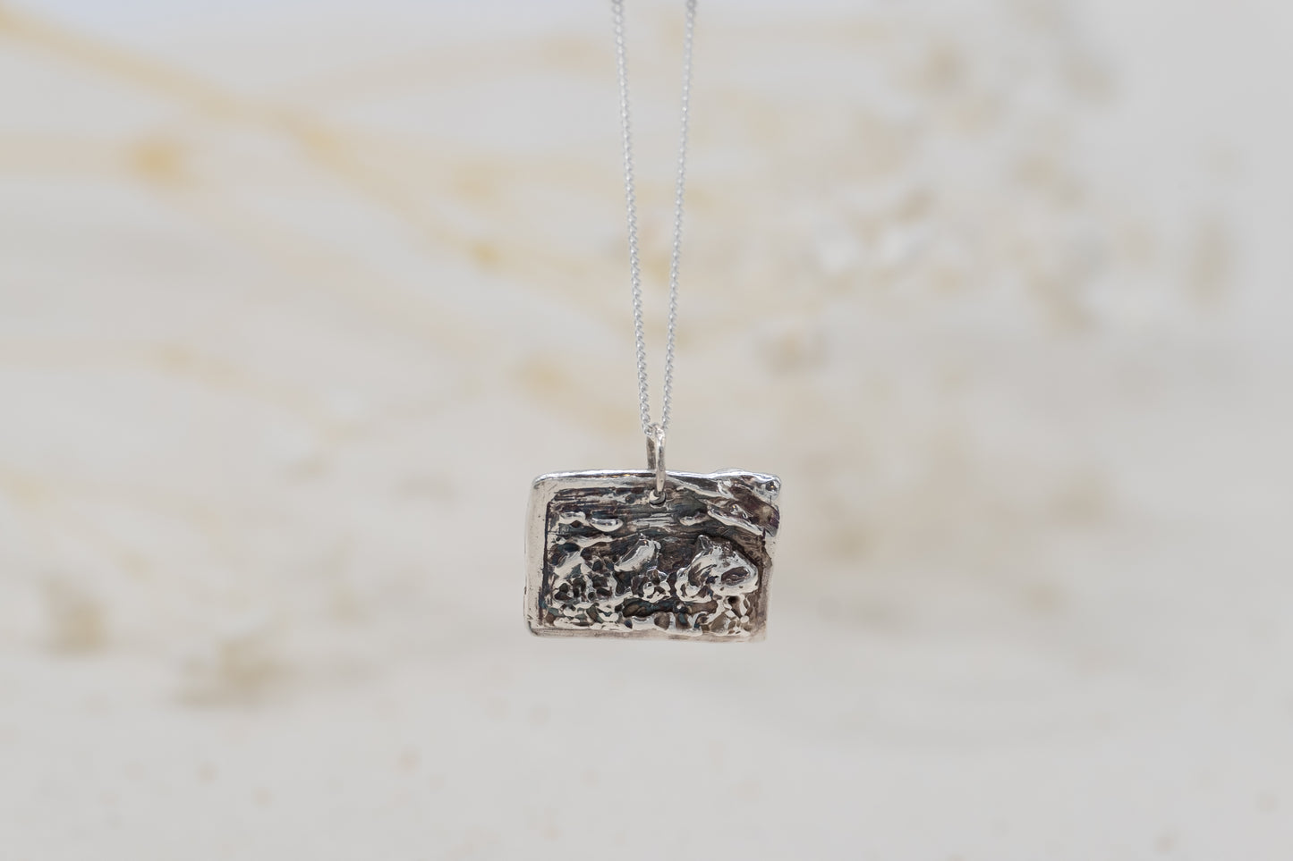 a customizable necklace with a silver postcard