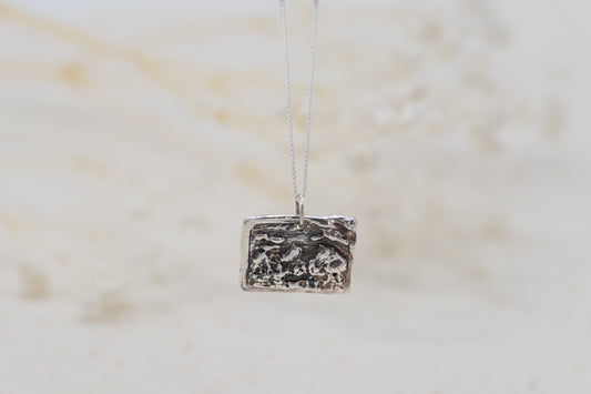 a customizable necklace with a silver postcard
