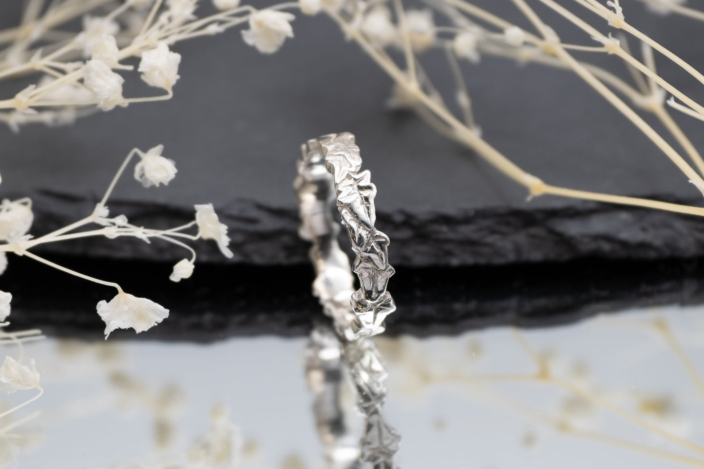 a slim ivy leaf ring on a mirror with a slate and flowers in the background