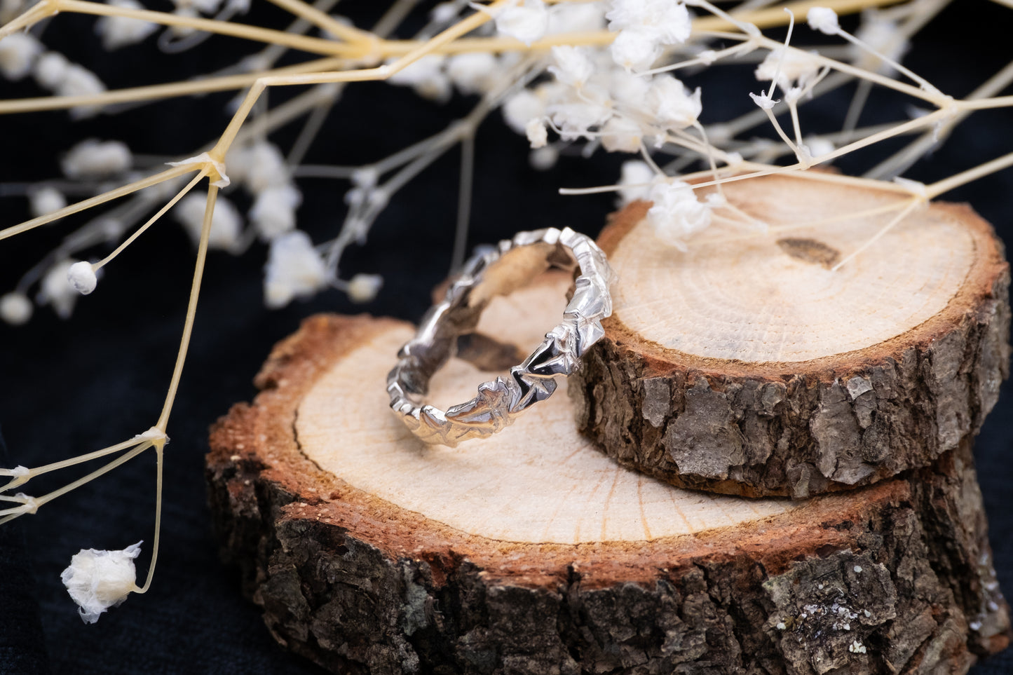 a silver ivy leaf ring on wood with flowers