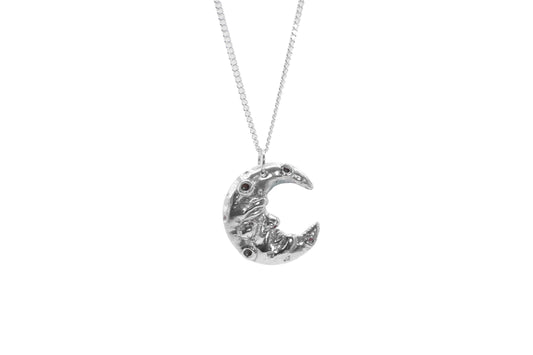 a silver man in the crescent moon pendant on a white background