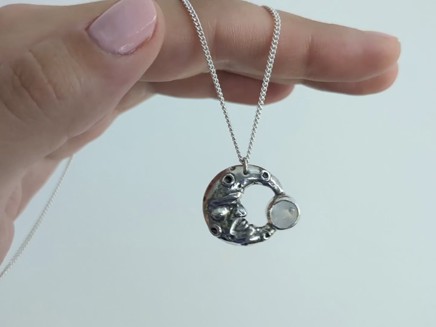 video of my silver man in the moonstone pendant hanging from my hand